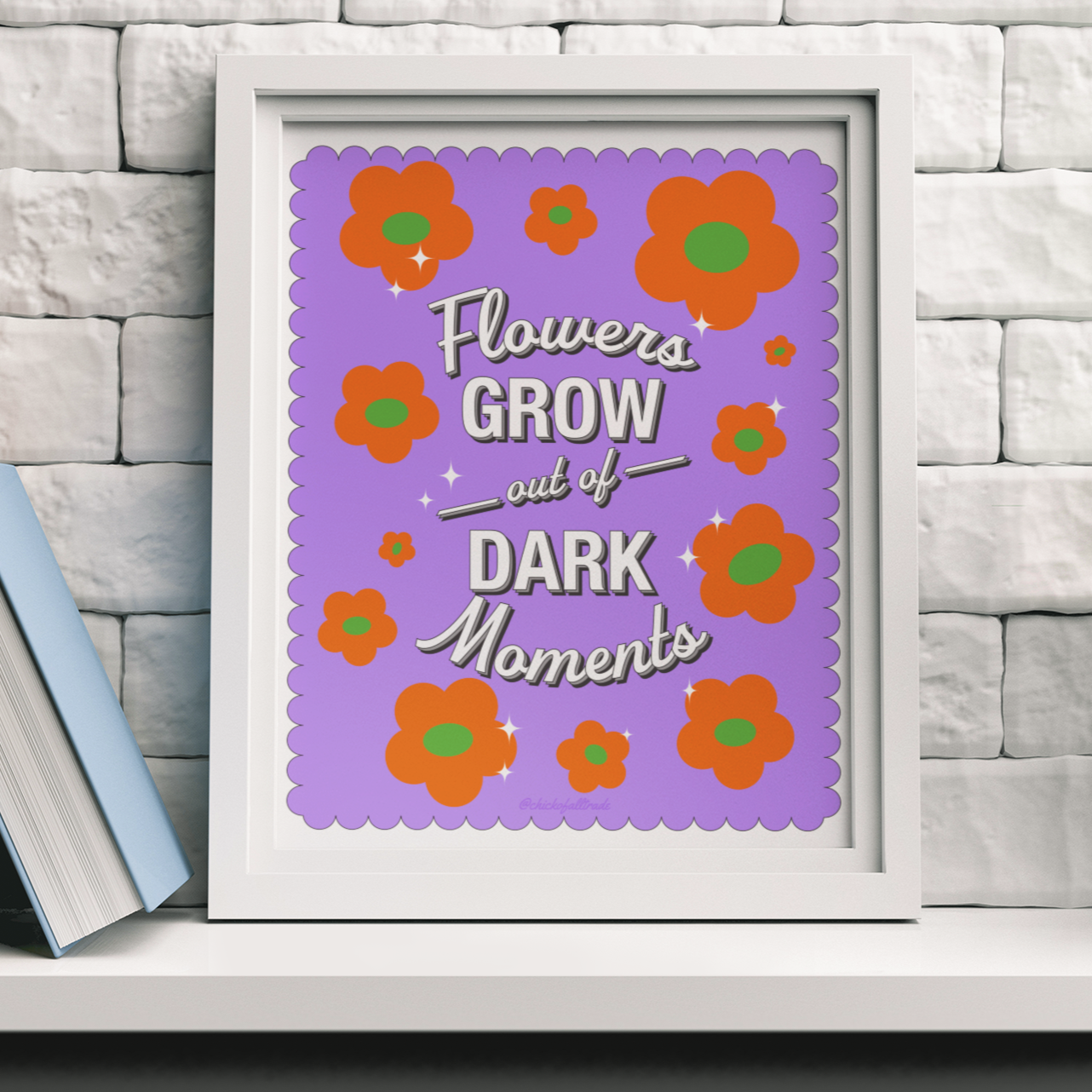 Framed print with floral design and motivational quote on a shelf with books