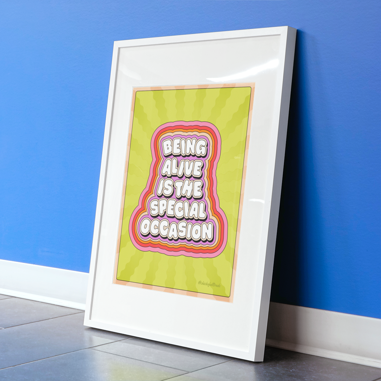 Framed artwork with 'Being Alive is the Special Occasion' text on a blue wall.